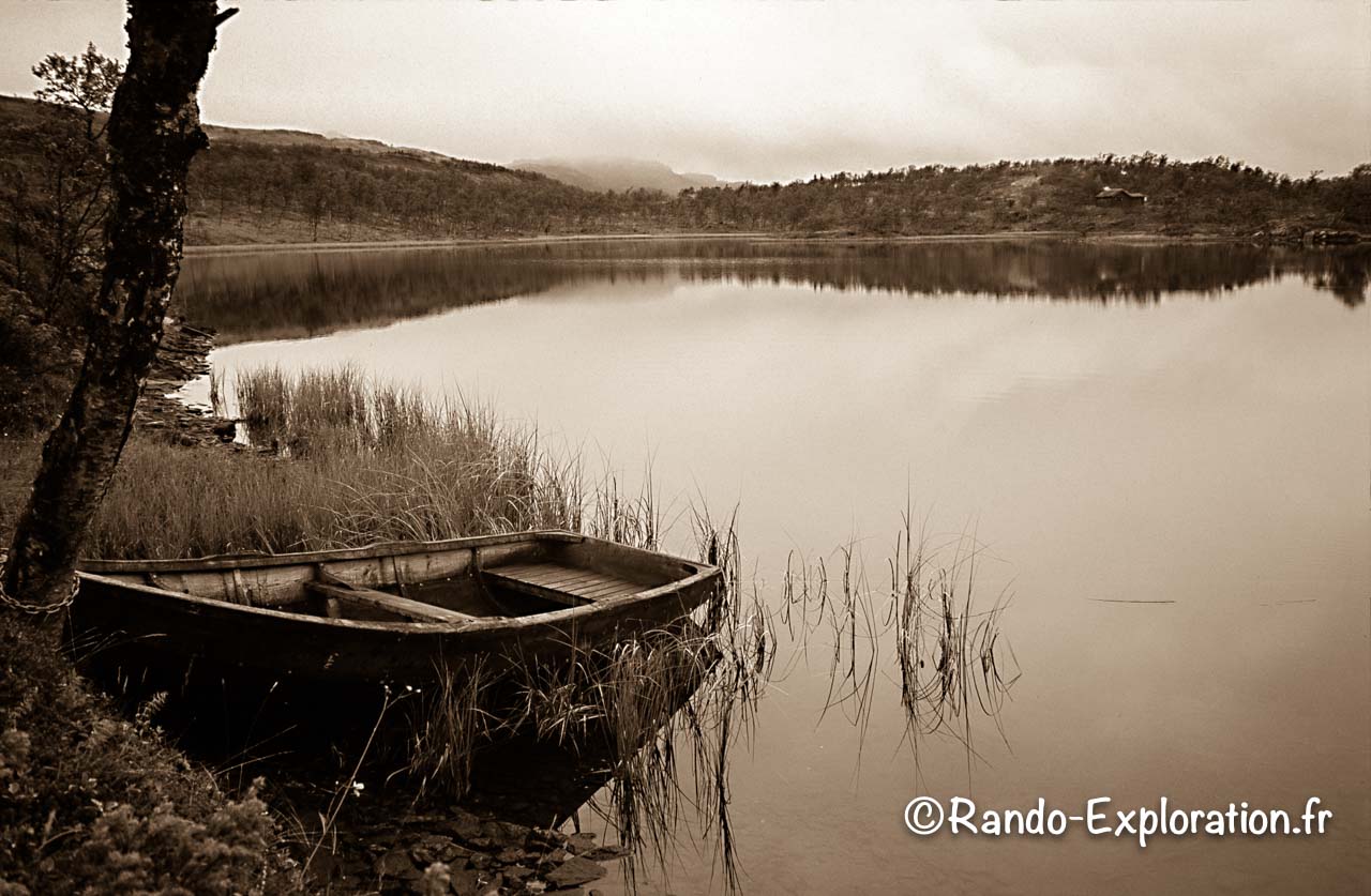 Une barque amarée sur la rive d'un petit lac, photo en sépia