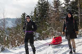 Couple tractant une pulka avec un enfant à bord